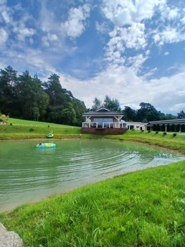 a house on the river with a boat in the water at Lion Sauna in Vydmantai