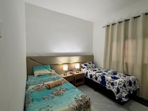 1 dormitorio con 2 camas y 1 mesa con 2 lámparas en Bella House, en Inhambane
