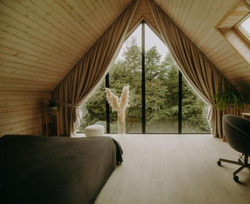 a bedroom with a bed and a large window at Domki Momenty in Słajszewo