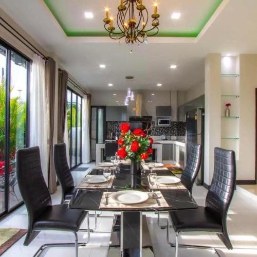 a dining room with a table and chairs and a kitchen at Kathu V pool villa 170 in Kathu