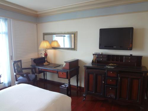 a hotel room with a bed and a desk and a television at Tuli Imperial in Nagpur