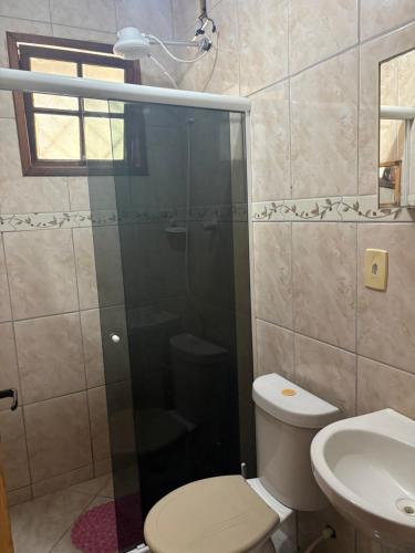 a bathroom with a shower and a toilet and a sink at Casa simples e aconchegante em Unamar - Cabo Frio in Tamoios