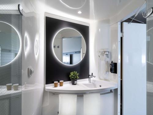 a white bathroom with a sink and a mirror at Ibis Barcelona Aeropuerto Viladecans in Viladecáns