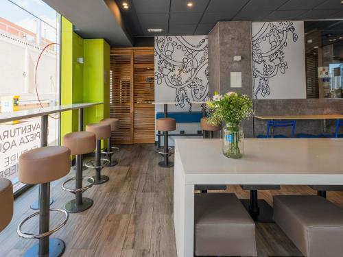 una sala de espera con una mesa y taburetes en Ibis Budget Madrid Calle Alcalá, en Madrid