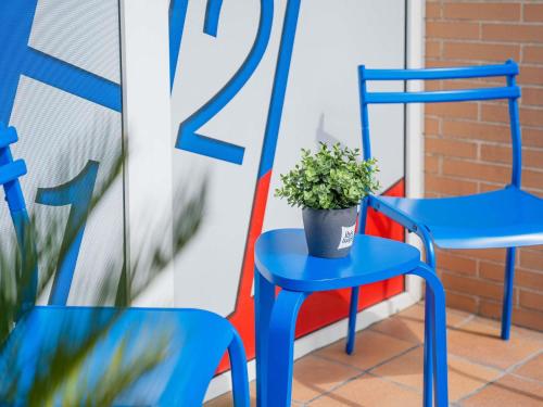 deux chaises bleues et une plante en pot sur un porche dans l'établissement Ibis Budget Madrid Calle Alcalá, à Madrid