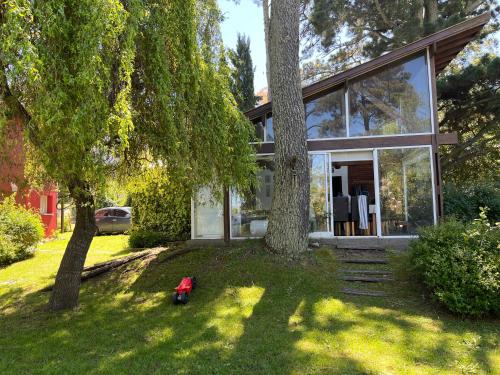 Ein Haus mit einem Baum und einem roten Spielzeug im Garten in der Unterkunft casa Sierras in Sierra de los Padres
