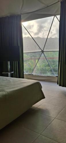 - une chambre avec une grande fenêtre et un lit dans l'établissement Romantic Dome Escape in Saint-Martin, à Saint-Martin
