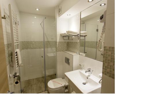 W łazience znajduje się umywalka, toaleta i lustro. w obiekcie Hotel Kragujevac w mieście Kragujevac