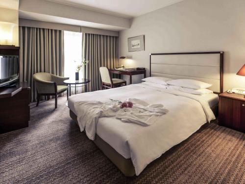 a hotel room with a large bed and a desk at The Cypress Mercure Hotel Nagoya in Nagoya