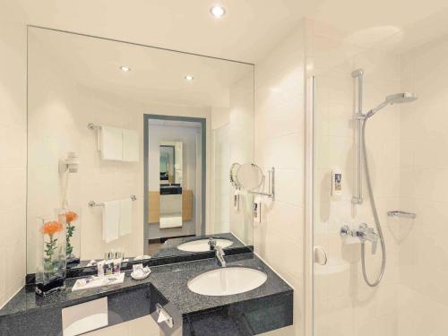 a bathroom with two sinks and a shower at Mercure Hotel Düsseldorf City Nord in Düsseldorf