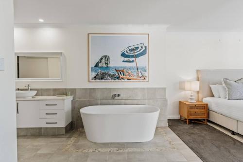 ein Badezimmer mit Badewanne und Waschbecken und ein Bett in der Unterkunft Sundrift - Sophisticated Beachside Retreat with Pool in Dunsborough