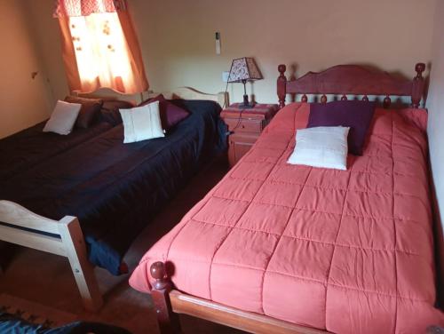 a bedroom with two beds with red comforters at Casa de campo Villa El Perchel in Huacalera