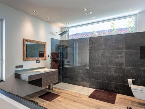 a bathroom with a shower and a sink and a mirror at Alpin Chalet ARTE in Söll