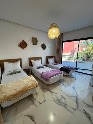 Hostel Atlantic view Tamraght في Tamraght Ouzdar: غرفة بثلاث اسرة وثريا