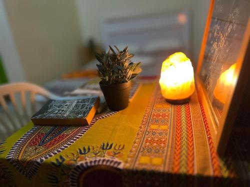 una mesa con una vela y un libro y una lámpara en casavaz, en Tarrafal