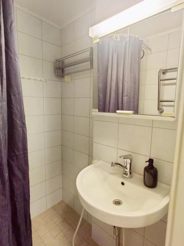 a white bathroom with a sink and a mirror at Cozy Nordic Studio in the Heart of Helsinki in Helsinki