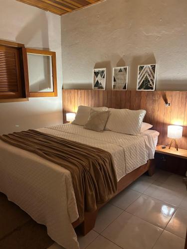 a bedroom with a large bed and two pictures on the wall at Recanto no Centro in São Francisco Xavier