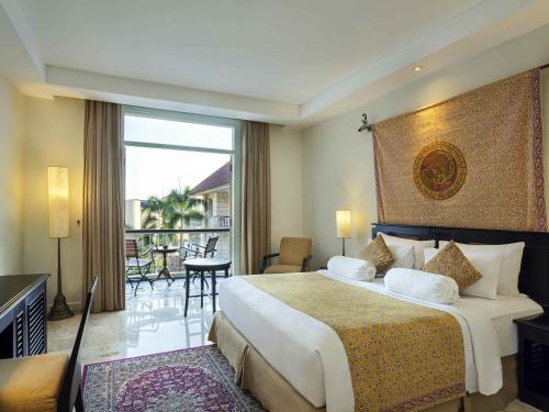 a hotel room with a large bed and a balcony at The Phoenix Hotel Yogyakarta - Handwritten Collection in Yogyakarta
