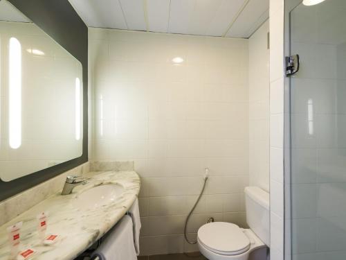 a bathroom with a sink and a toilet and a mirror at ibis Campinas in Campinas