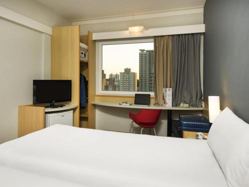 a hotel room with a bed and a desk and a window at ibis Campinas in Campinas