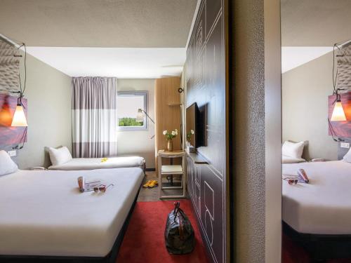 een hotelkamer met twee bedden en een spiegel bij ibis Manosque Cadarache in Manosque
