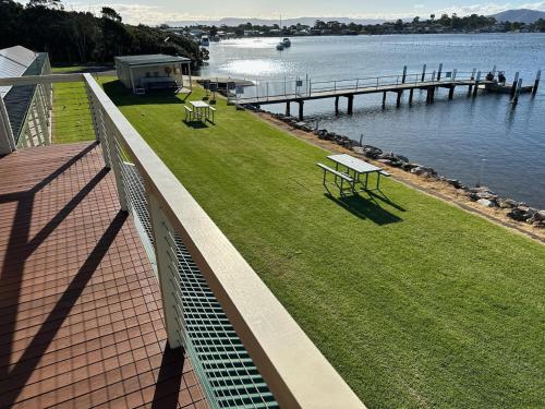 a balcony with a bench and a dock and water at Coral Tree Lodge in Greenwell Point
