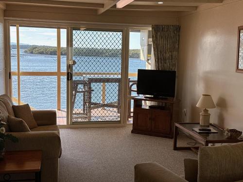 a living room with a television and a view of the water at Coral Tree Lodge in Greenwell Point