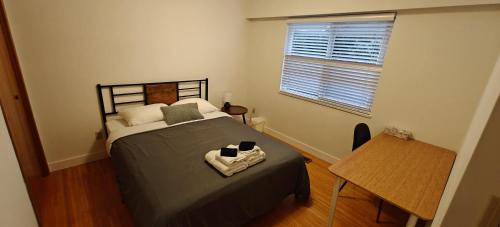 a bedroom with a bed and a table and a window at Spacious Family Room with Shared Washroom in Vancouver