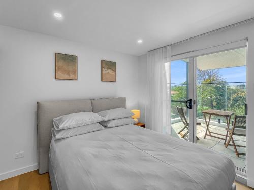 ein weißes Schlafzimmer mit Bett und Balkon in der Unterkunft Modern 4-Bed Townhouse with Water Views in Malua Bay