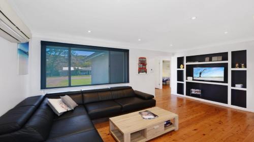a living room with a black leather couch and a table at Copa Beach House - Family in Copacabana