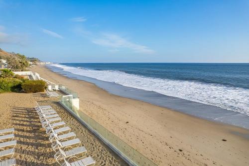 ein Strand mit weißen Liegestühlen und dem Meer in der Unterkunft Aquareve in Malibu Beach