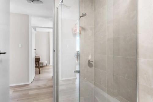 une douche avec une porte vitrée dans une salle de bain dans l'établissement Bright Beachside Escape at The Entrance, à Entrance