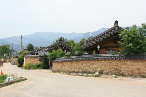 a building with a stone wall next to a street at Jinrae Lee's Traditional House in Boseong