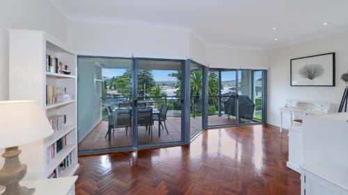 a dining room with glass doors and a table at The Point On Cliff - Two Levels and Views in Avoca Beach