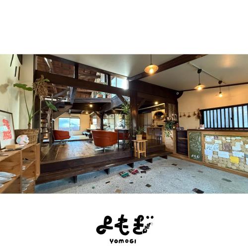 a living room with wooden floors and chairs and a room at YOMOGI GUESTHOUSE in Tokoname