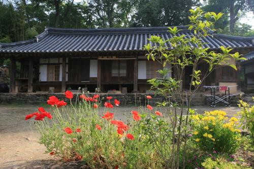 a garden with red flowers in front of a house at Jinrae Lee's Traditional House in Boseong