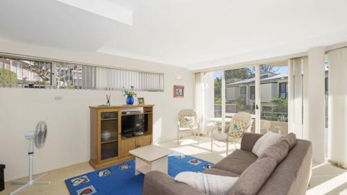 a living room with a couch and a tv at Sandpiper 4 - Great Location in Avoca Beach
