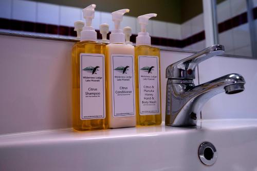 trois bouteilles de savon posées sur un lavabo de salle de bain dans l'établissement Wilderness Lodge Lake Moeraki, à Haast