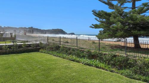 a garden with a fence and the beach at Ocean Sunrise - Magical in Avoca Beach