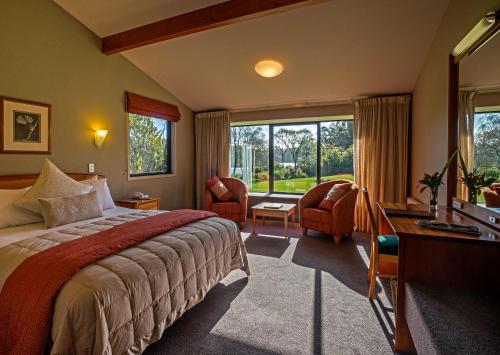 une chambre d'hôtel avec un lit, un bureau et des fenêtres dans l'établissement Wilderness Lodge Lake Moeraki, à Haast