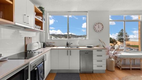 a kitchen with white cabinets and a clock on the wall at Seaview 5 - Great Beach Views in Avoca Beach