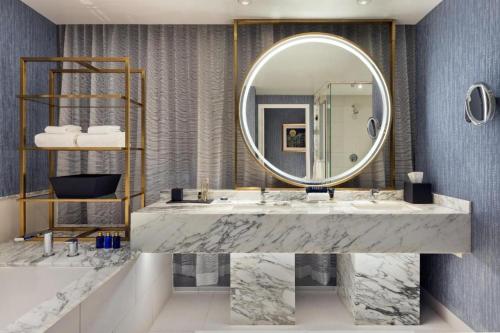 a bathroom with a large mirror and a marble sink at Fontainebleau Las Vegas, MICHELIN Key Award Hotel in Las Vegas
