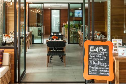 a restaurant with a chalkboard sign in front of a table at Cmor by Recall Hotels SHA Extra Plus in Chiang Mai