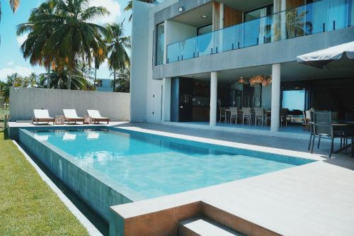 a swimming pool in front of a house at Casa Waua | PÉ NA AREIA, rooftop, borda infinita in Barra do Camaragibe