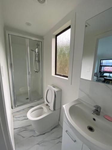 a white bathroom with a toilet and a sink at 2-bed granny flat near Auckland Airport in Auckland