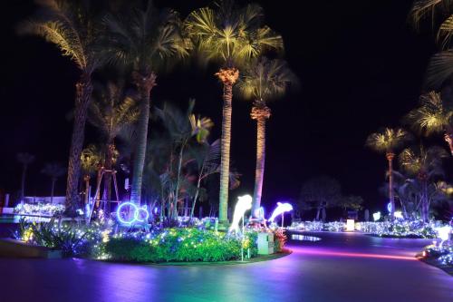 um parque com palmeiras e luzes à noite em Ryukyu Hotel & Resort Nashiro Beach em Itoman