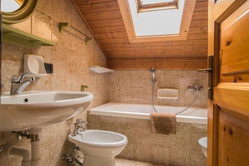 リヴィーニョにあるMansardalpinaのバスルーム(洗面台、トイレ、バスタブ付)