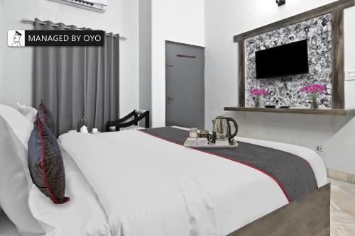 ein Schlafzimmer mit einem weißen Bett und einem Fernseher in der Unterkunft FabHotel Classic Holidays in Jaipur