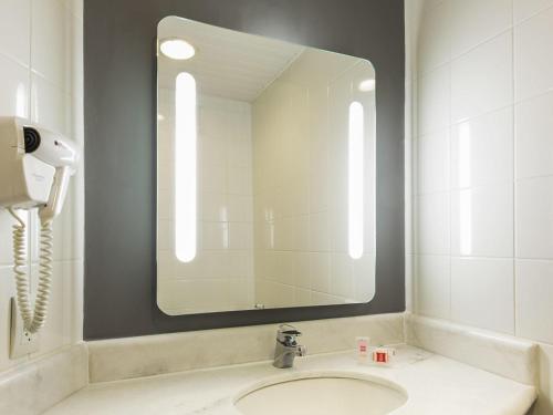 a bathroom with a sink and a large mirror at ibis Sao Jose dos Campos Colinas in São José dos Campos