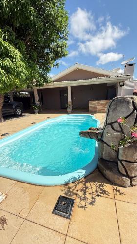 a blue swimming pool in front of a house at Casa ampla e confortável próxima ao shopping pátio in Boa Vista
